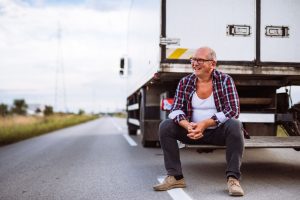 Homem sentado ao lado de traseira de caminhão